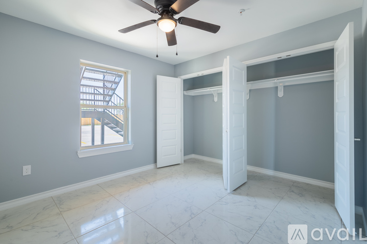 A room with a ceiling fan and a window with a view of a building.