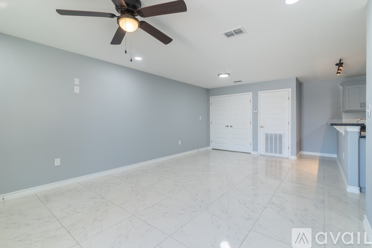 A spacious room with a ceiling fan and marble flooring.