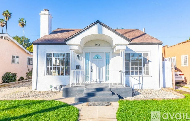 A white house with a black roof and a glass door is for sale.