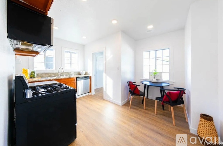 A kitchen with a black stove top oven and a dining table with four chairs.