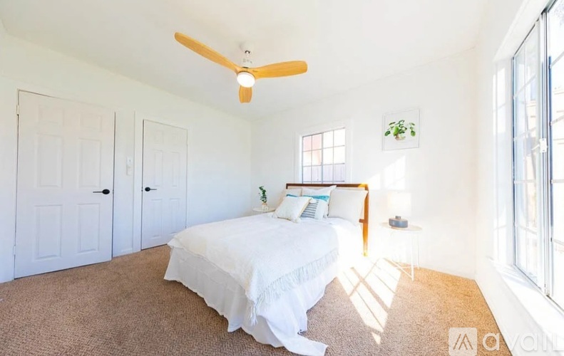 A bedroom with a bed, a ceiling fan, and a window.