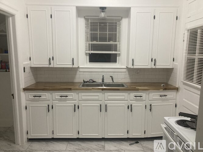 A kitchen with white cabinets and a wooden countertop.