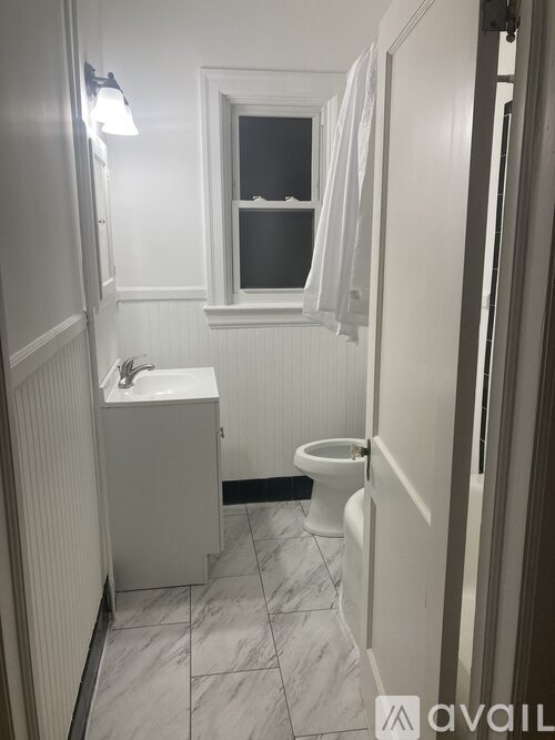 A bathroom with a toilet, sink, and a window.