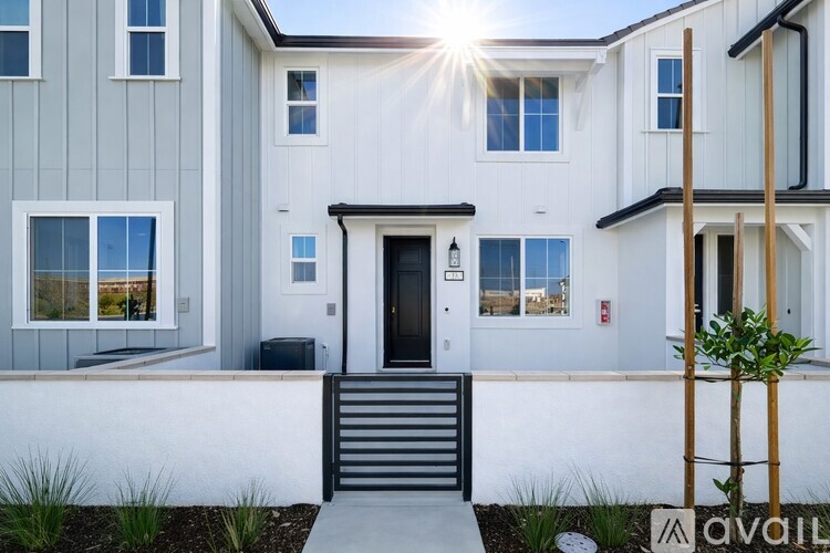 A modern house with a white front door and a small garden in front.