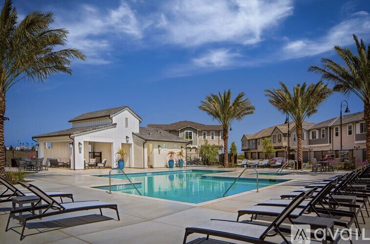 A pool surrounded by lounge chairs and palm trees.