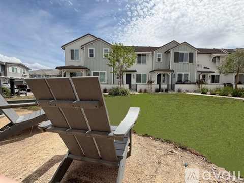 A spacious room with wooden flooring and a kitchen area with a refrigerator, microwave, and oven.