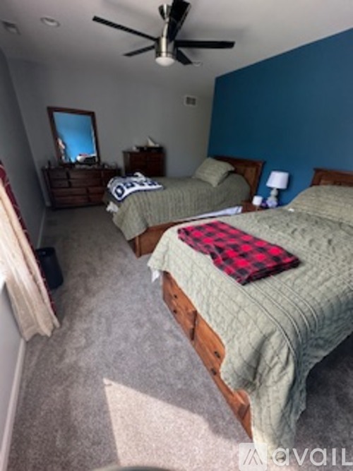 A bedroom with two beds and a ceiling fan.