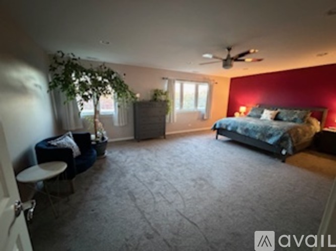 A bedroom with a bed, a chair, and a ceiling fan.