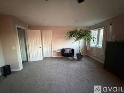 A living room with a grey carpet and a black speaker.