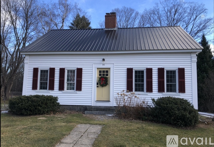 A white house with red shutters and a yellow door.