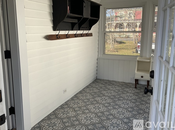 A room with a grey patterned floor and a window showing a view of a building outside.