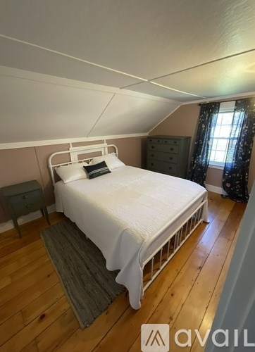 A bedroom with a white bed and wooden flooring.
