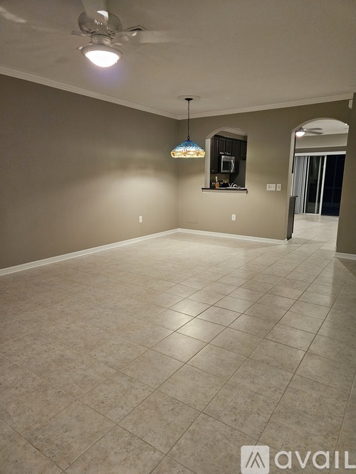 A spacious room with a ceiling fan and a chandelier hanging from the ceiling.