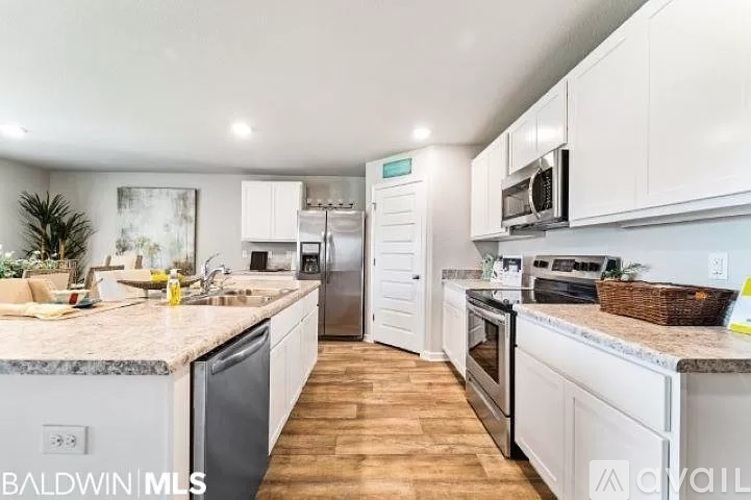 A kitchen with white cabinets and a marble countertop.