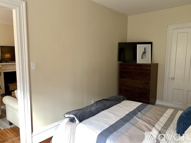 A bedroom with a bed, a dresser, and a television.