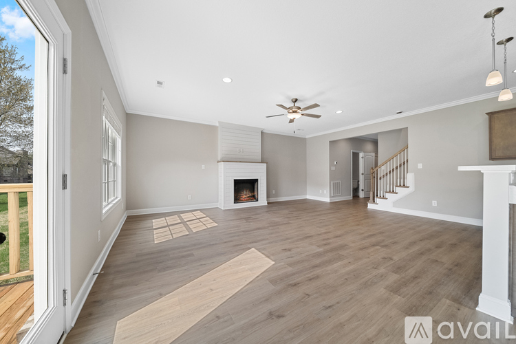 A spacious living room with a fireplace and a staircase.