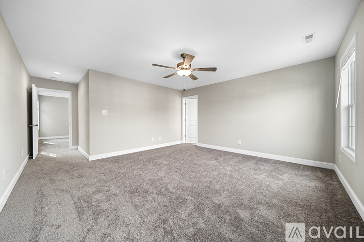 A spacious room with a ceiling fan and carpeted floor.