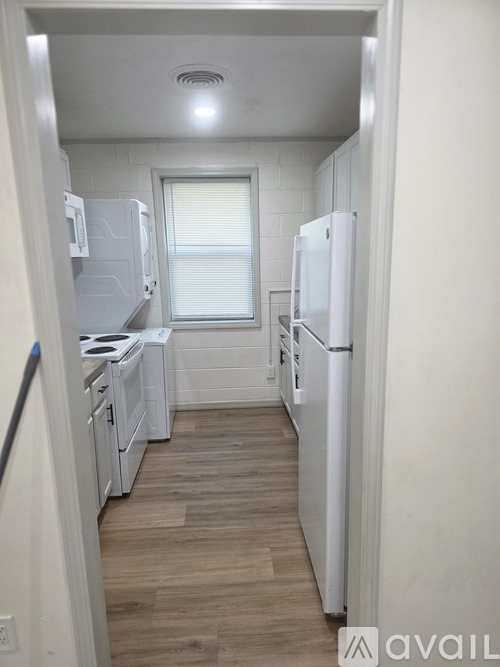 A small kitchen with white appliances and wood flooring.