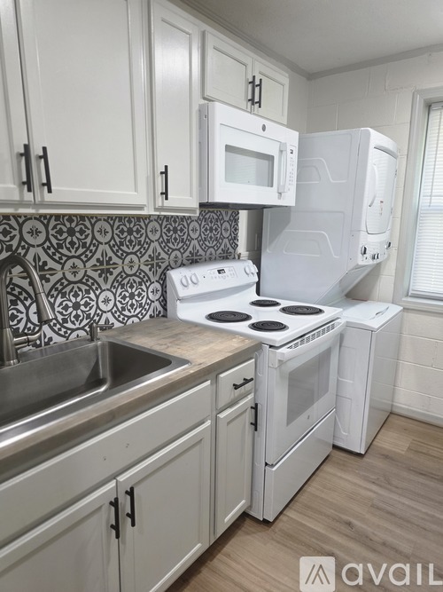 A kitchen with white cabinets and a patterned backsplash.