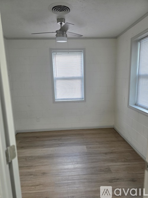 A room with a ceiling fan and two windows.