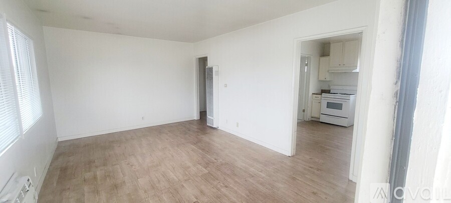 A spacious room with wooden flooring and white walls.