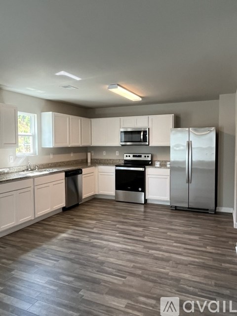A kitchen with white cabinets and a wooden floor.