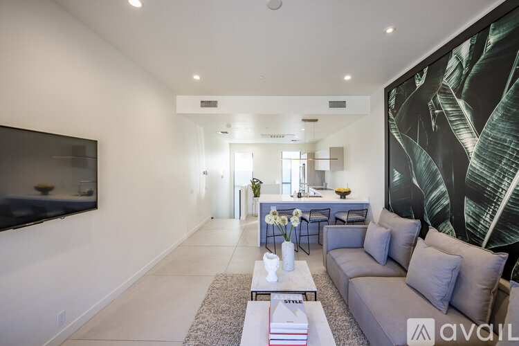 A modern living room with a grey sofa, a coffee table, and a large painting on the wall.