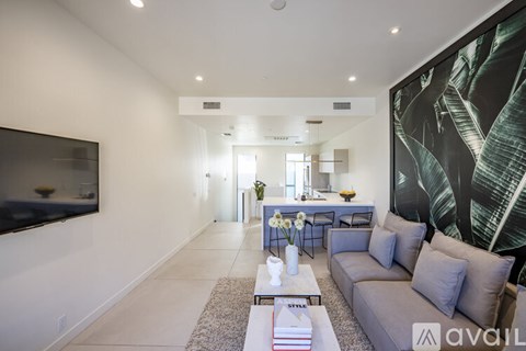 A modern living room with a grey sofa, a coffee table, and a large painting on the wall.
