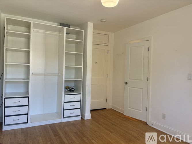 A room with a white door and a white shelf with drawers.