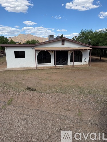 A white house with a brown roof and a brown fence.