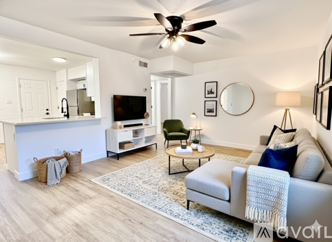 A living room with a grey couch and a white ceiling fan.