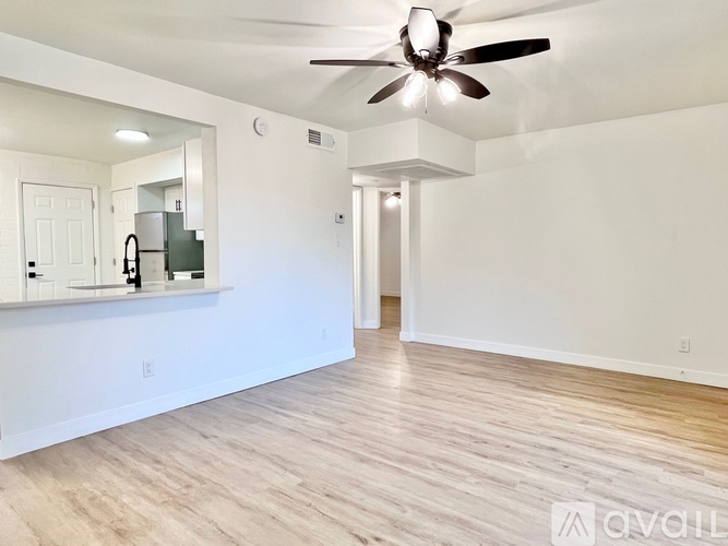 A spacious room with a ceiling fan and wooden flooring.