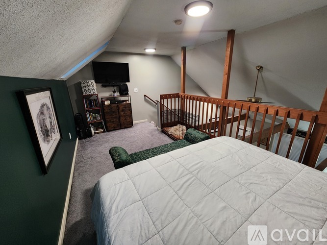A bedroom with a bed, a staircase, and a television.