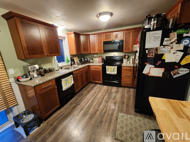 A kitchen with wooden cabinets and a black fridge.