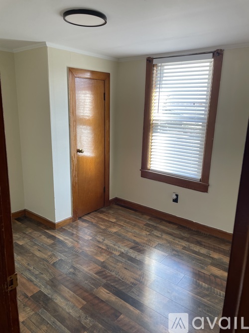 A room with a wooden door and a window with blinds.