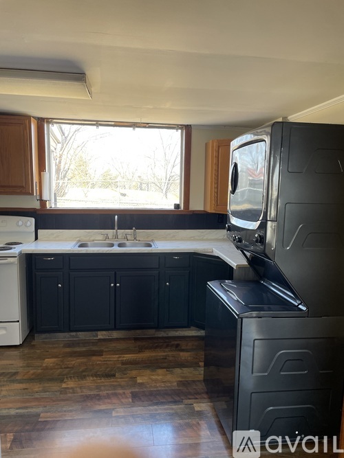 A kitchen with dark cabinets and a white dishwasher.