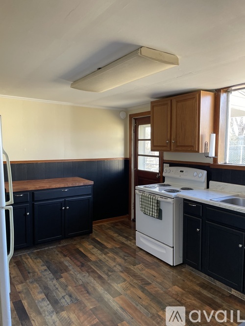 A kitchen with a white stove top oven and black cabinets.