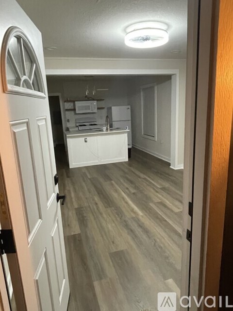 A kitchen with white cabinets and a wooden floor.