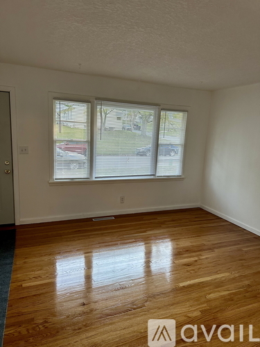 A room with wooden floors and a window showing a view of a street with cars.