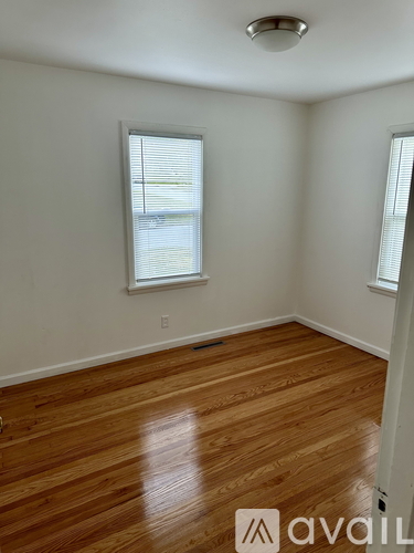 A room with wooden flooring and a window with blinds.