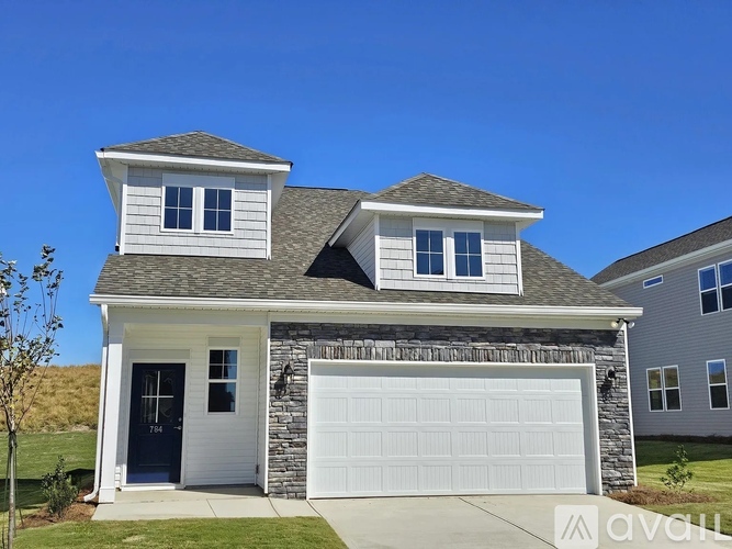 A two-story house with a garage and a stone wall.