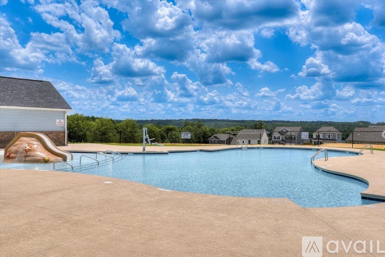 A large outdoor swimming pool with a slide and a sunbathing area.