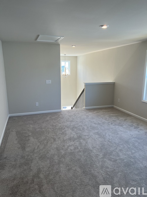 A spacious room with a carpeted floor and a staircase leading to another room.