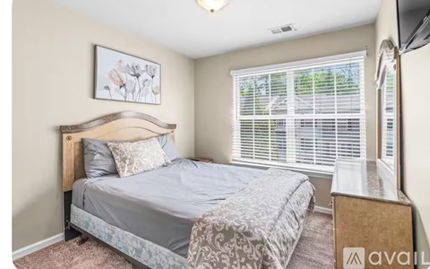 A bedroom with a bed, nightstand, and window with blinds.