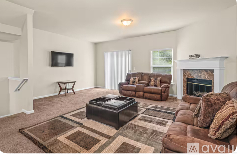 A living room with a brown leather couch, a coffee table, and a flat screen TV mounted on the wall.