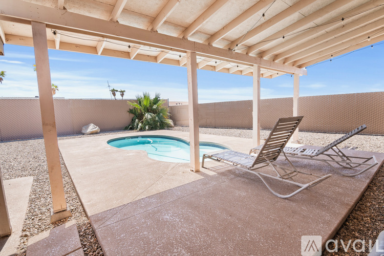 A patio with a pool and chairs.