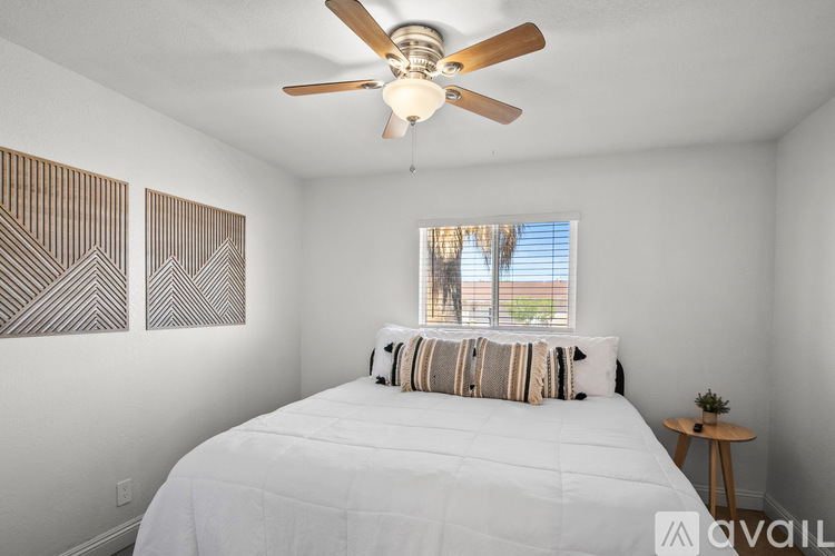 A bedroom with a white bed and a ceiling fan.