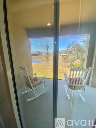 Two chairs are on a balcony with a view of a field and trees.