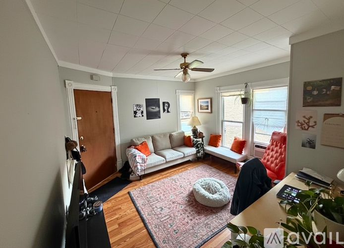 A living room with a couch, a chair, a rug, and a ceiling fan.