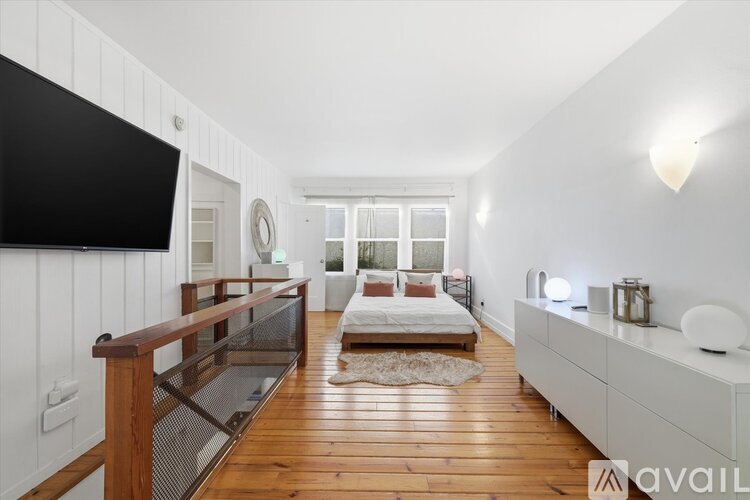 A modern bedroom with a large bed and a flat screen TV mounted on the wall.